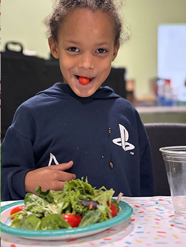 Child eating a salad at the South End Children's Cafe