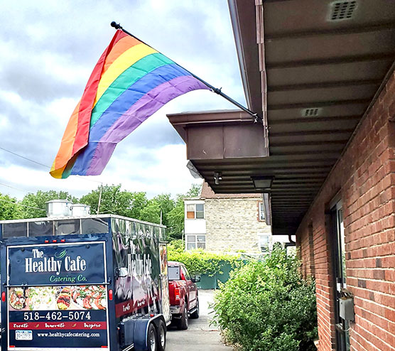 The Healthy Cafe Catering Co. trailer parked underneat a rainbow prode flag outside the South End Children's Cafe