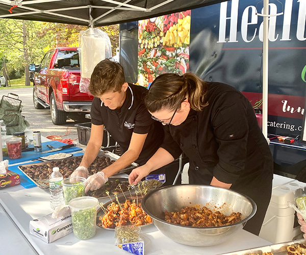 Healthy Cafe Catering staff plating appetizers at an outdoor catering event