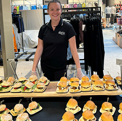 Healthy Café Catering Co. staff member standing behind a table of plated sandwiches